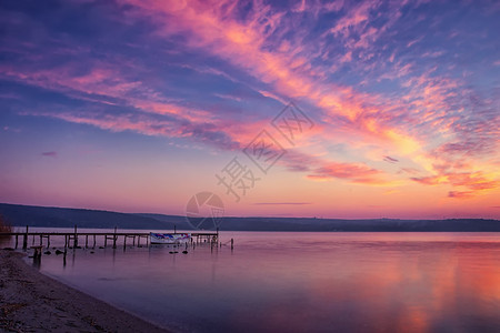 美丽而平静的日落在湖上有码头和船感人的岩石桥图片