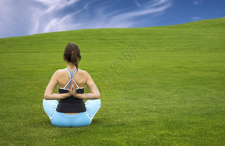 友好美丽的运动女子在美丽的绿草地上做瑜伽制造吸引人的图片