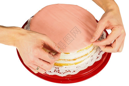 快乐的制作自专业蛋糕面包师在用粉红玛西潘覆盖奶油蛋糕时做最后触碰图片