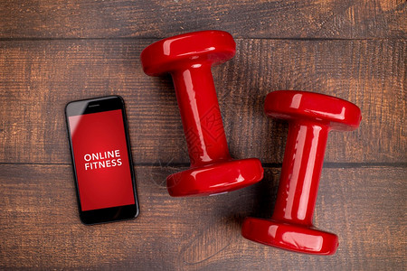 用于培训室内在线健身方案的红哑铃和智能手机木林背景App用于培训室内在线健身方案家庭在线锻炼TopViewCovid19Coro图片
