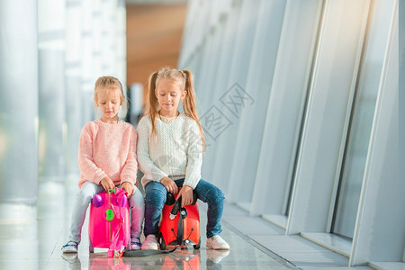 在大国际机场靠近窗户的机场适居少女和在机场的适居小女孩她们的行李等待登机候的终端童年运输图片