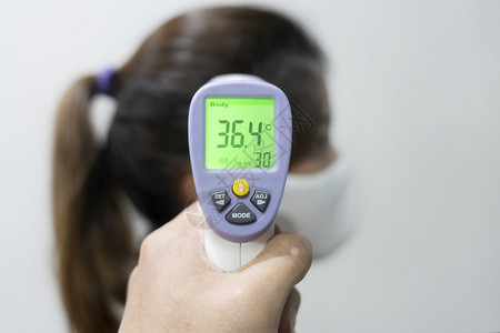 使用电子红外线温度计检查身Tp保护免受Corona伤害的妇女前头手观扫描感染面具图片