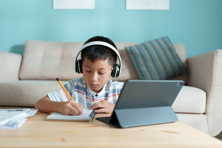 技术互联网教育亚洲男孩与在线教师一起学习和做功课使用平板数字电脑在家用耳机药片图片