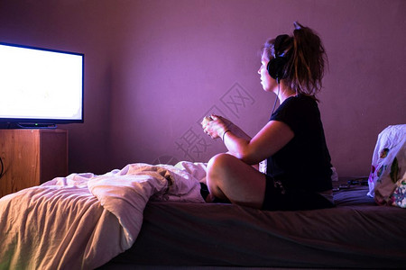 戴耳机的青少年玩家在中使用游戏控制台器在LED电视上观看游戏和娱乐概念游戏和娱乐概念趣技术操纵杆图片