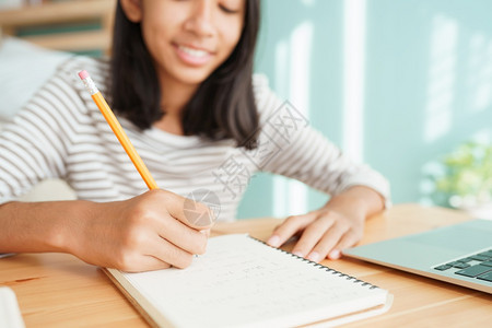 孩子沟通基本的做家庭作业和用笔记本电脑在上写的亚洲女孩手持式家庭在线学习概念图片