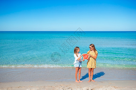 海滩上的小姑娘们手里拿着一小片西瓜图片