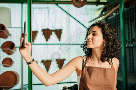 电话装饰露天市场女人在自己的小陶瓷店里自拍图片