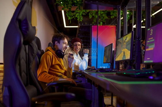 互联网在游戏俱乐部虚拟娱电子体育锦标赛网络体育生活方式中玩两个青年游戏家男在网吧闲暇时间2个青年游戏家在俱乐部里玩个人电脑咖啡店图片