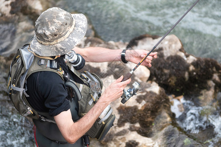 男在河里钓鱼的人水渔夫展示技术使用竿爱好和体育活动快乐的飞图片