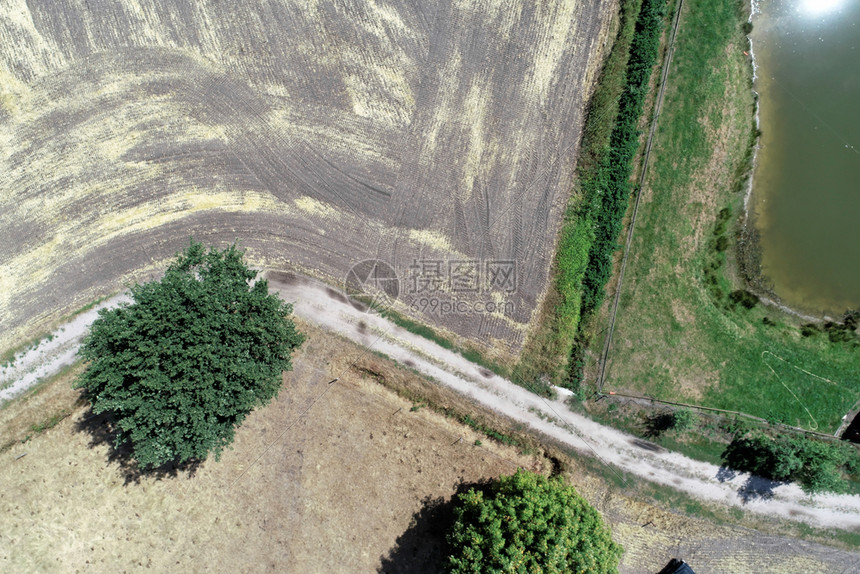 垂直空中观察在收割田和草地旁边的一条道路上方有一个小稳定的草地靠近狭窄的护堤池塘场地收获图片