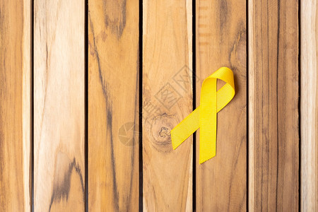 孩子慈善机构支持9月预防日儿童癌症意识月和世界癌症日概念关于木桌背景的黄丝带用于支助生活和疾病的人9月预防日儿童癌症意识月和世界图片