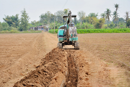 重的机器园艺人强迫一个小搬运工挖树底的花园沟农业图片
