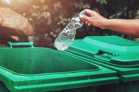妇女手拿垃圾塑料瓶装在公园打扫时把垃圾放进桶为了乐观的生态图片
