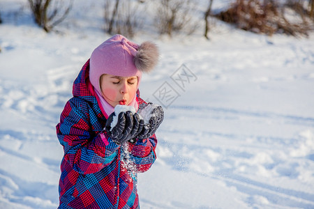 快乐的女孩在阳光明媚的冬日扔雪冷冻天成人图片