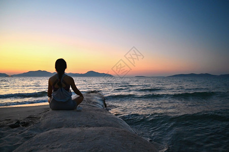 练习摆姿势红色的妇女冥想日落时在海滩的边放松瑜伽健康和SPA的概念图片