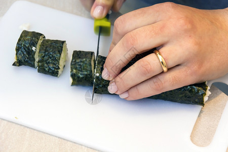 食物孩子在家里切寿司卷在割板上母亲图片