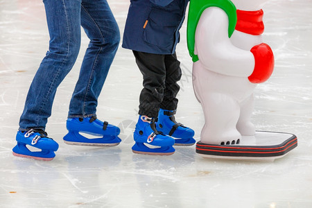抓住学习可选择的在滑冰场冬天一个幼儿在成年父母的支持下学会滑冰并坚持玩具帮工体育生活方式和休闲复制空间选择焦点在滑冰场的关闭冬季图片