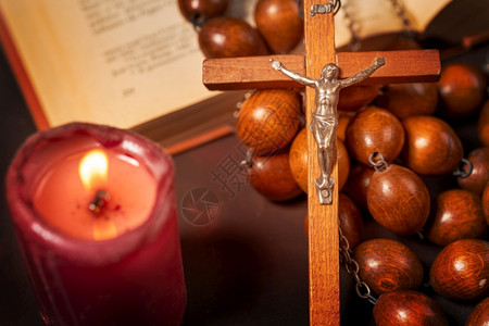 崇拜祈祷与红蜡烛和圣经书精神氛围宗教概念交叉的大木罗萨里珠子和智慧图片