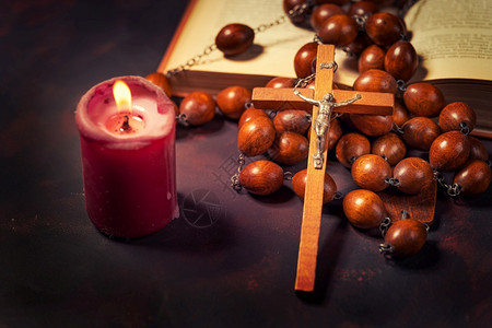 奉献木头天主教与红蜡烛和圣经书精神氛围宗教概念交叉的大木罗萨里珠子和图片