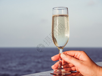 快乐的放松在海浪背景下游轮露天甲板上盛着一杯美丽的香槟可爱女人观光近视休闲概念和旅行观享受美丽香槟的可爱女人欢快的士香槟杯子手背景图片