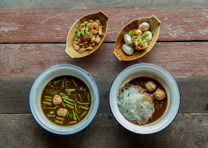 开胃菜辛辣的肉汤泰国风格船面在铁碗中的KuayTiewRua与猪叉和生锈木桌上的猪肉球图片