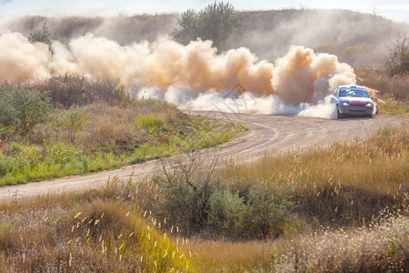 快速地锦标赛车运动达斯帝在拉里道和一堆尘土05转弯时运动车做了许多灰尘05年体育车在拉里赛道的交汇时间图片