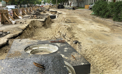 沥青流走城市收集器的水泥块井和管道位于街路上修复城市下水道的公路上挖掘沟附近b市政收集器的水泥砖井和管道户外图片