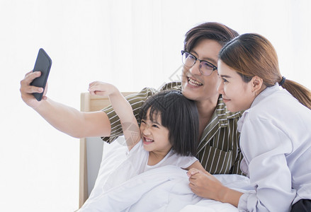 一个亚洲家庭起在卧室里花时间和合影拍照幸福生活女儿图片