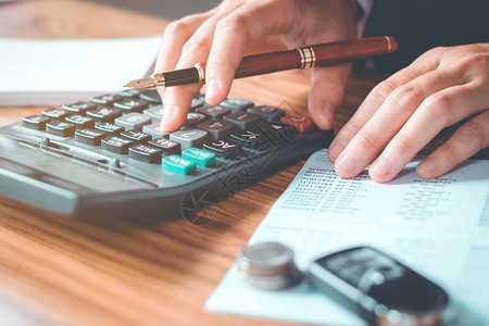 债务数投资商业家手握办公室计算器和成本财务数据分析计在木制办公桌上图片