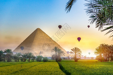 夏天在绿地的Egyptian金字塔上方的空气球位于雾中清晨幻想风景的绿地田里有Egyptian金字塔地平线景观图片