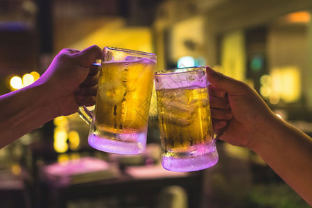 低的生活两杯啤酒在朋友之间一起欢呼在低光酒吧的朋友和餐厅放松饮酒的概念寒冷图片