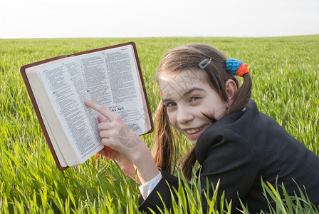 带着圣经的女孩躺在草地上学校蓝色的闲暇图片