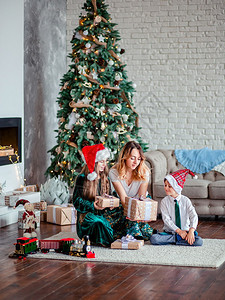 幸福的家庭母亲和孩子坐圣诞树下打开礼物图片