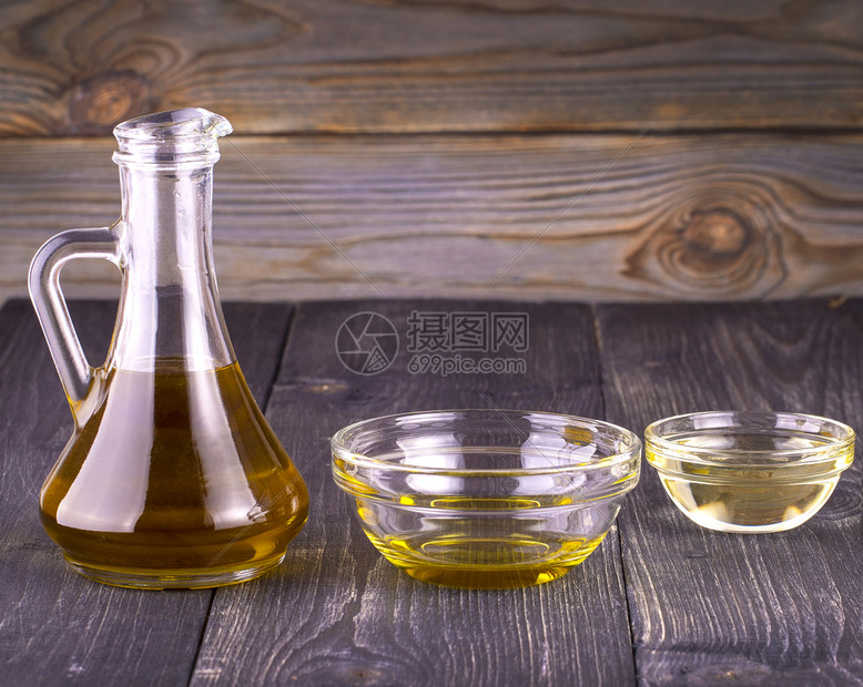 老的水壶在一个小玻璃杯里煮植物油在旧木制桌边的酒壶里煮蔬菜油木制的图片