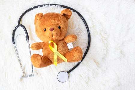 人们活的帕努瓦9月儿童癌症意识和世界癌症日概念白背景的听诊器关于熊娃的黄色丝带用于支持儿童生活和疾病9月儿童癌症意识和世界癌症日图片