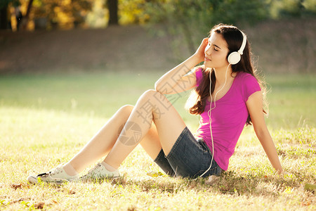 草地上听音乐的年轻女人图片