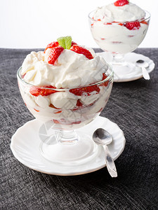 两碗有草莓和奶油在黑暗背景的一碗草莓和胶水杯上浆果鞭打冰淇淋图片