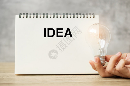 新的有创造力纸手持灯泡在桌上的笔记本新想法创意新想象力灵感分辨率战略和目标概念图片