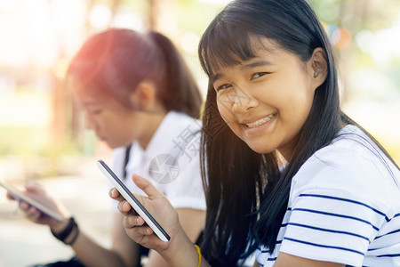 聊天聪明的网站带着智能手机的年轻亚洲青少笑脸手持智能电话图片