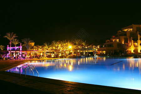 旅游享受度假的泳池和晚间酒店人们上在游泳池附近放松晚间酒店的灯光在夜晚游泳池水中反射图片