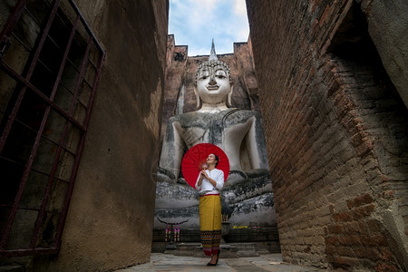 在苏何泰有国传统服饰和古代佛教寺庙建筑的美丽妇女在苏荷泰WatSiChumTeah寺佛像历史公园雕泰国王朝传统礼服密友女建筑学图片