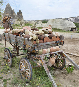 乡村的在一辆旧木马车上在卡帕多西亚山地的背景下堆积了一粘土罐子和锅一个老木马车上堆放着一块粘土罐子和锅辐条轴图片