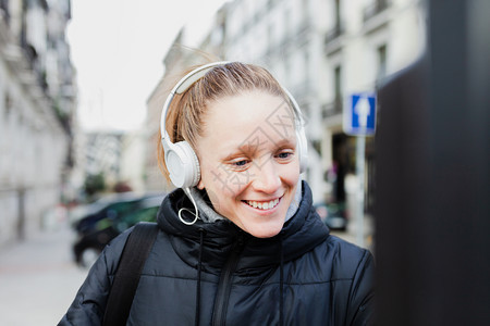 年轻金发美女在城里付停车费脸上戴着耳机的夹克脸型惊讶的常设吸引人辫子图片