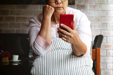 沮丧的成年老妇女感到无趣绝望地仰智能手机因听到坏消息而抑郁的中年女强调悲伤的中年女陈在线的士背景图片