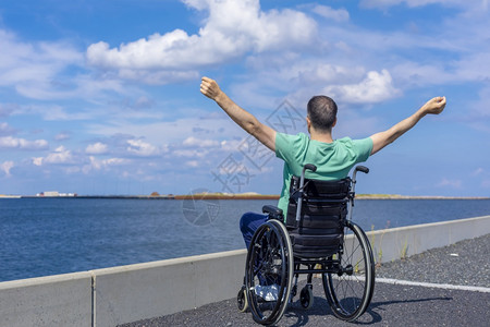 坐着闲暇旅行移动和自由概念在海上欣赏轮椅的残疾男子截瘫图片