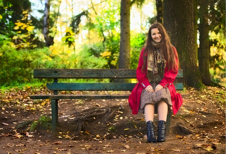 坐着美丽的女孩在魔法秋天公园的长椅上黑色十月图片