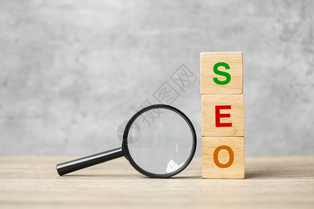 保持排行信息SEO搜索引擎SEO最佳优化文本木立方块和手握表Idea战略广告营销关键词和内容概念上的放大玻璃图片