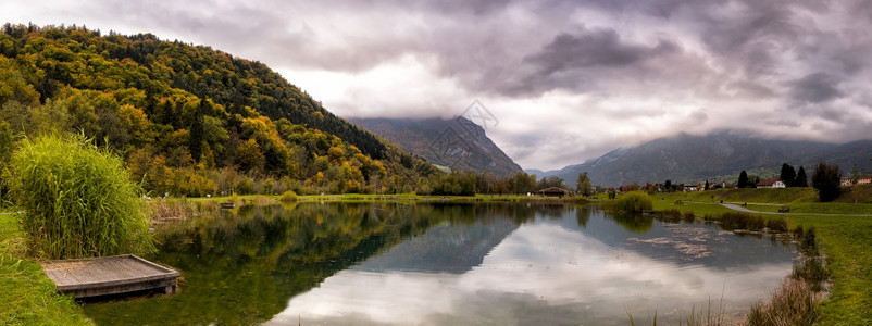 在阿尔卑斯山有绿树的湖上山丘反射绿色勘探徒步旅行图片