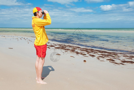 穿关注海上形势的年轻男青救生员制服玻璃图片