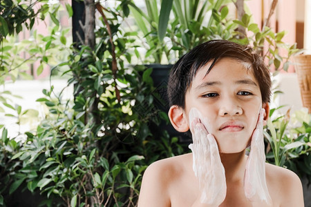 关闭亚洲男孩的脸部正在清洗他的脸用一个泡沫清洁剂洗脸化妆品干净的漂亮图片